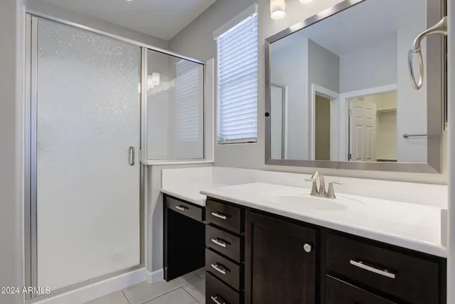 a bathroom with a granite countertop sink a mirror and a shower