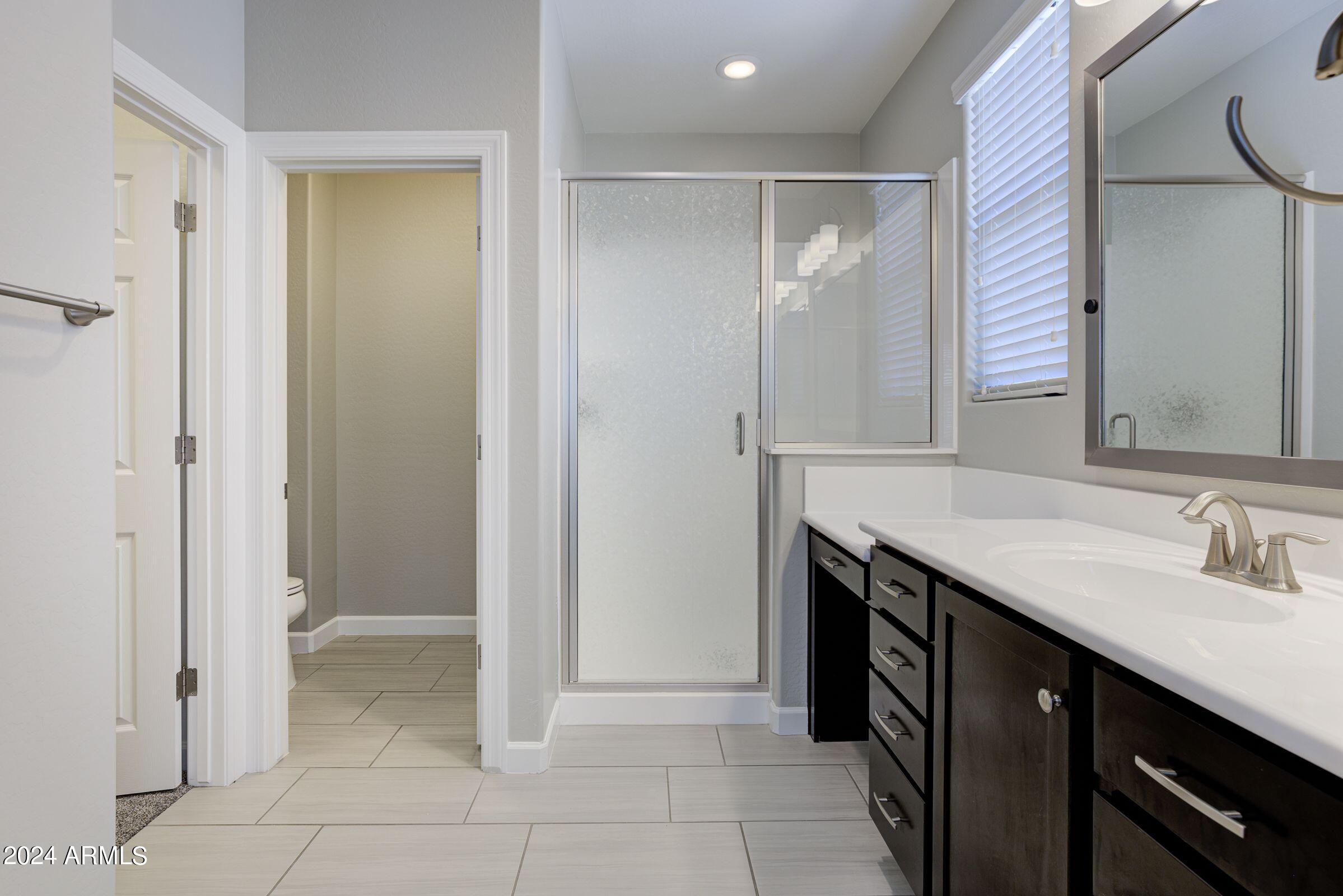 4777 South Fulton Ranch Boulevard, Unit 2066 Chandler, AZ 85248 - Photo 27 of 46 a bathroom with a granite countertop sink a mirror and a shower