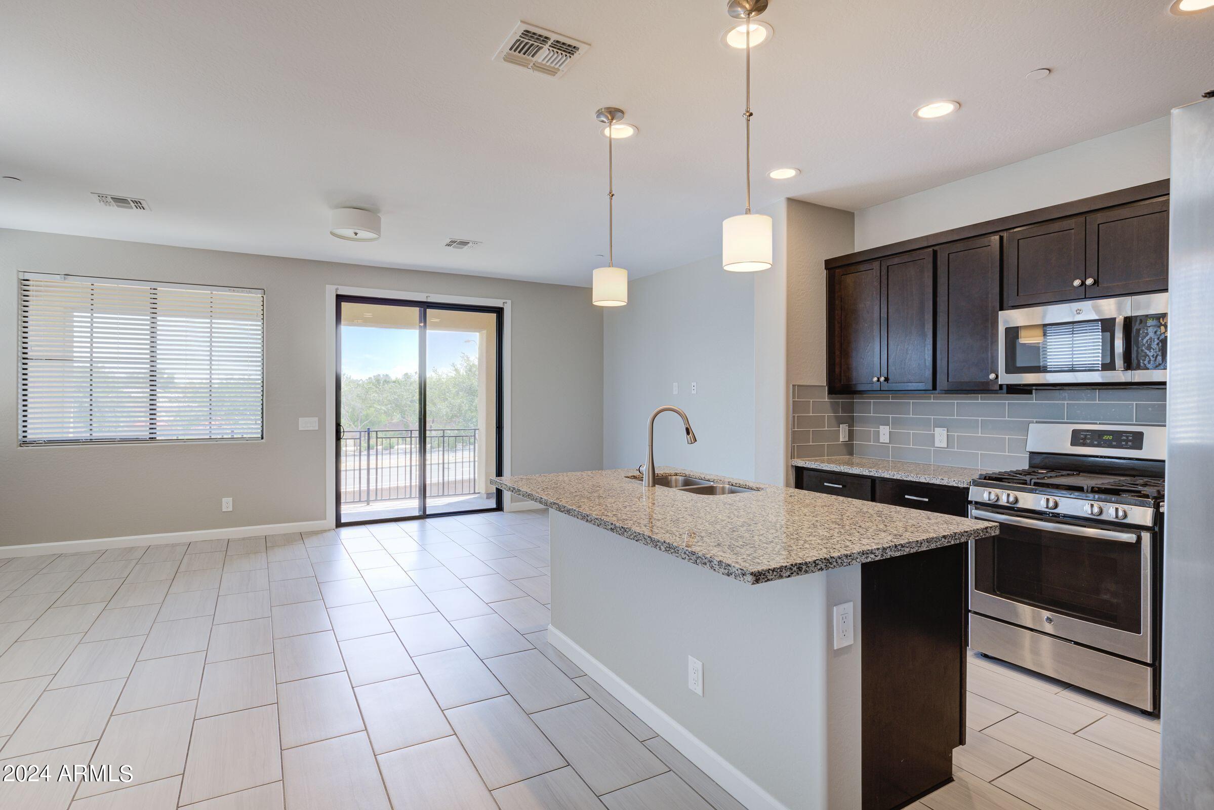 4777 South Fulton Ranch Boulevard, Unit 2066 Chandler, AZ 85248 - Photo 9 of 46 a kitchen with stainless steel appliances granite countertop a stove a sink and a microwave