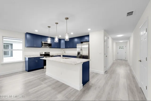 a large kitchen with stainless steel appliances kitchen island a large counter top and a wooden floors