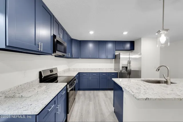 a kitchen with granite countertop a sink a counter top space cabinets and stainless steel appliances