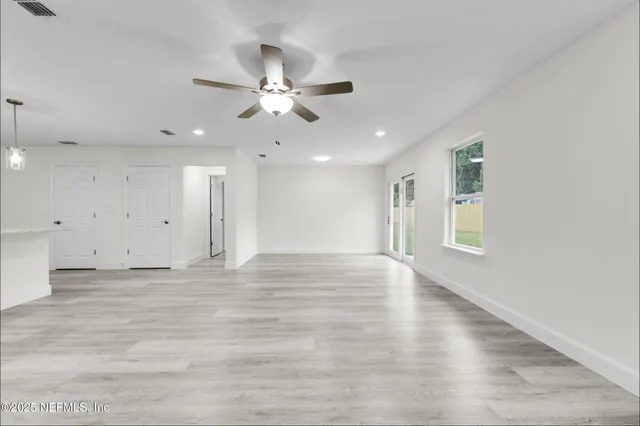a view of an empty room with window and wooden floor