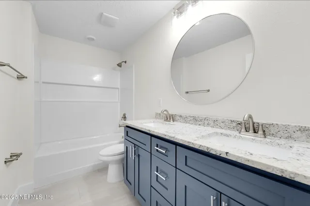 a bathroom with a granite countertop toilet a sink and a mirror