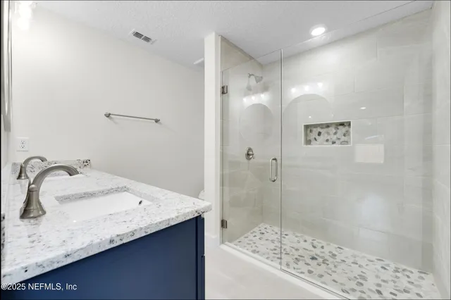 a bathroom with a granite countertop sink a mirror and shower