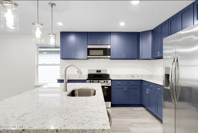 a kitchen with stainless steel appliances granite countertop a sink stove and refrigerator