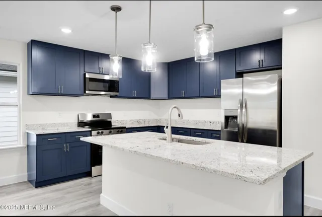 a kitchen with stainless steel appliances granite countertop a sink a stove a refrigerator and island