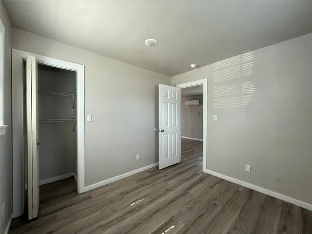 a view of an empty room with wooden floor and closet