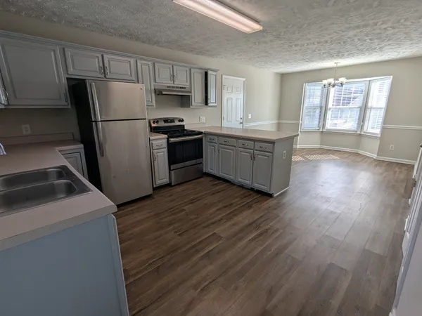 a kitchen with a refrigerator a microwave oven a sink with wooden floor and cabinets