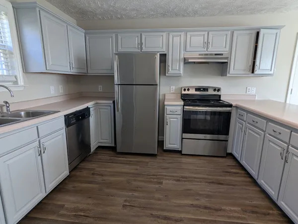 a kitchen with stainless steel appliances a sink cabinets and wooden floor