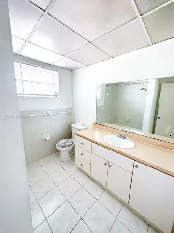 a bathroom with a granite countertop sink mirror vanity and toilet