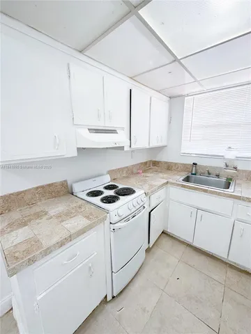 a kitchen with granite countertop white cabinets and white appliances