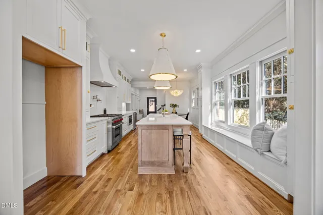 a large white kitchen with wooden floor and a window