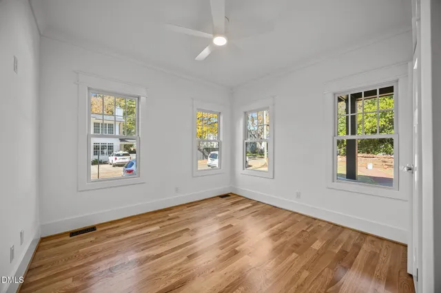 a view of an empty room with wooden floor and a window