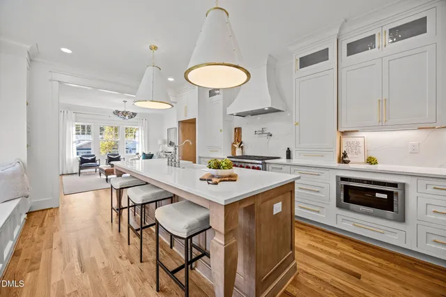 a kitchen with stainless steel appliances granite countertop a stove a refrigerator a kitchen island with white cabinets and wooden floor