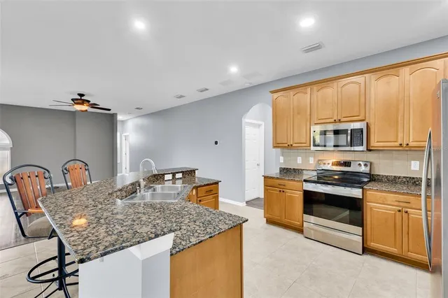a kitchen with stainless steel appliances granite countertop sink stove refrigerator and cabinets
