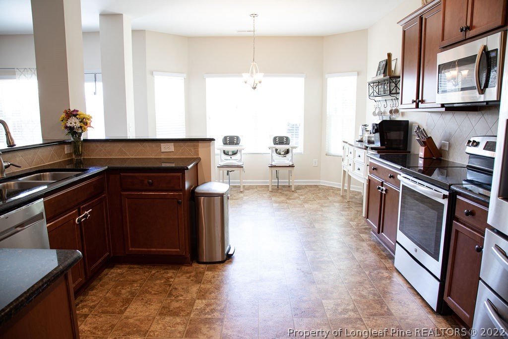 115 Stonehurst Drive Spring Lake, NC 28390 - Photo 19 of 50 a kitchen with stainless steel appliances granite countertop a stove a sink and a microwave