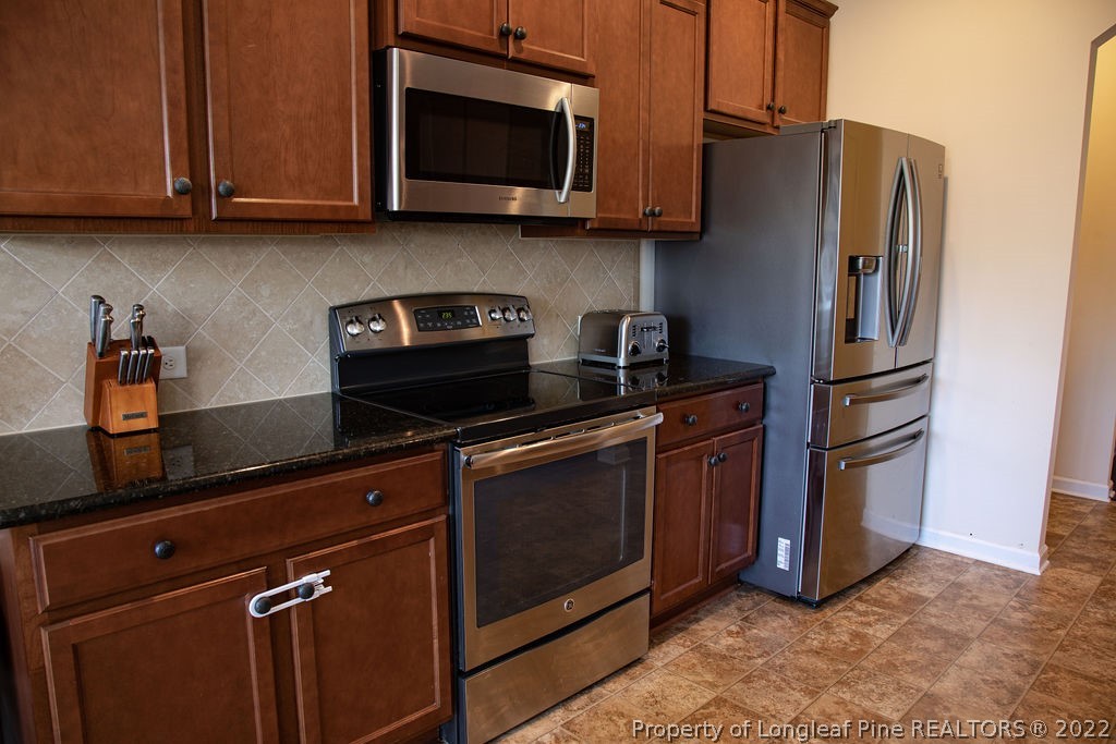 115 Stonehurst Drive Spring Lake, NC 28390 - Photo 21 of 50 a kitchen with stainless steel appliances granite countertop a stove microwave and refrigerator