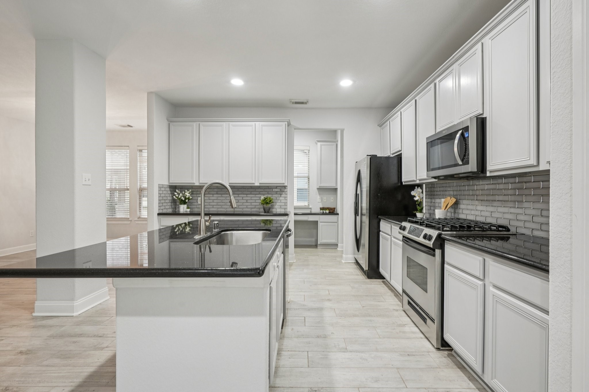 90 Panterra Way Spring, TX 77382 - Photo 11 of 43 a kitchen with stainless steel appliances granite countertop a stove top oven a sink a refrigerator white cabinets and couches with wooden floor