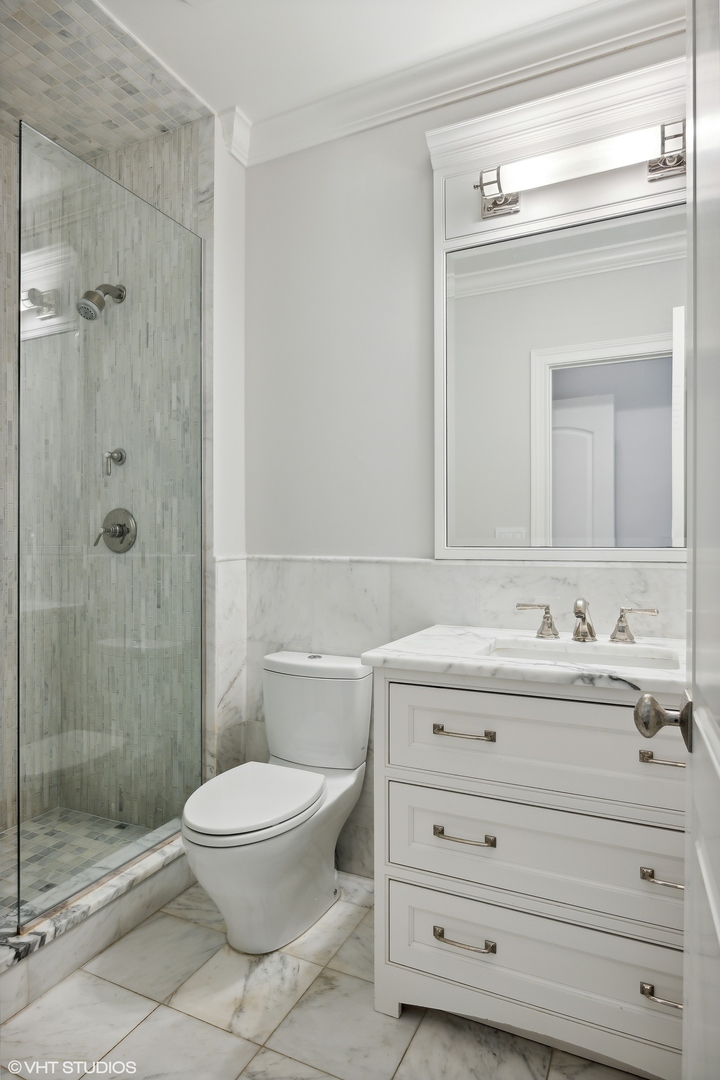 339 Linden Street Winnetka, IL 60093 - Photo 35 of 69 a bathroom with a granite countertop toilet a sink a mirror and shower