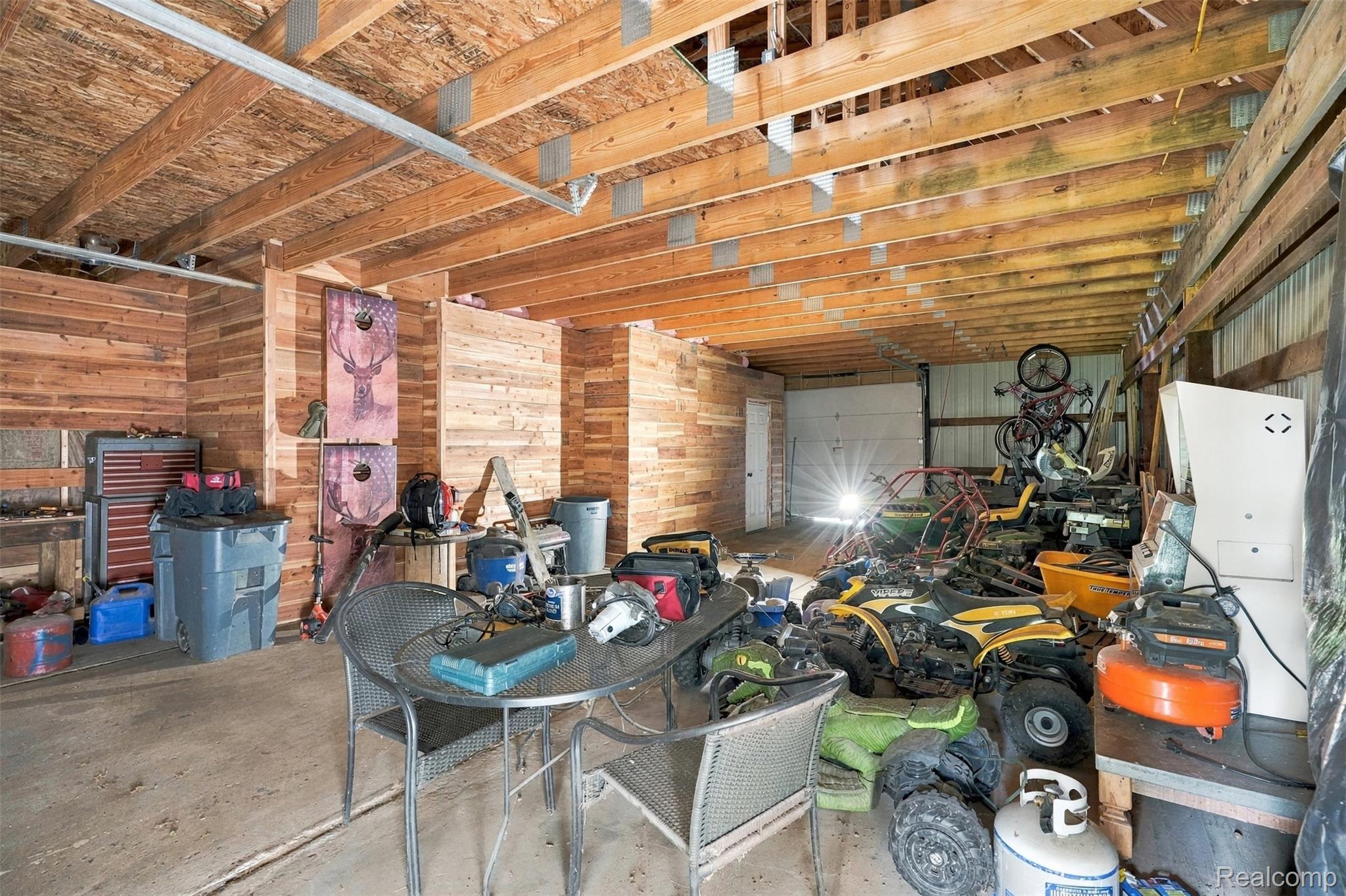 26516 Romine Road New Boston, MI 48164 - Photo 39 of 62 Spacious utility area featuring exposed wood beam ceiling, wood-paneled walls, and a concrete floor