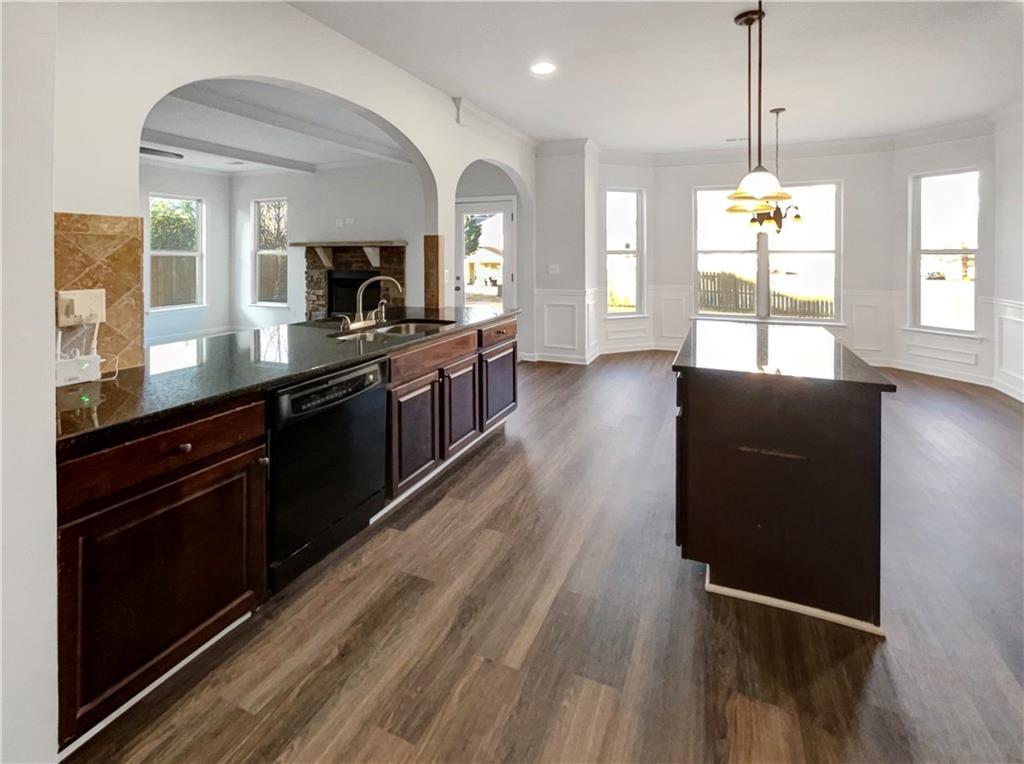 2879 Valaise Lane Lithonia, GA 30038 - Photo 6 of 25 a large kitchen with granite countertop a stove a sink dishwasher a microwave oven and a dining table with wooden floor