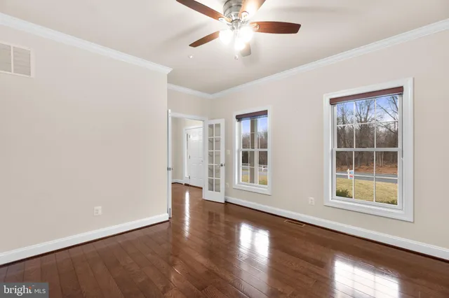a view of an empty room with a window and wooden floor