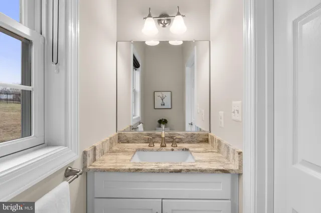 a bathroom with a granite countertop sink and a mirror