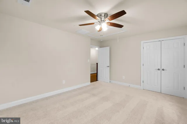 an empty room with closet and a chandelier fan
