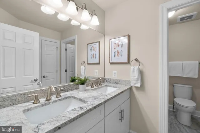 a bathroom with a granite countertop sink a toilet and a mirror