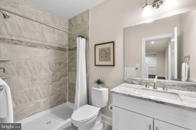 a bathroom with a granite countertop sink toilet a mirror a shower and a sink