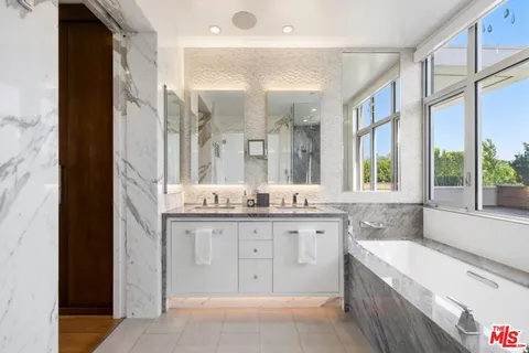 a bathroom with a granite countertop double vanity sink a mirror and a bathtub