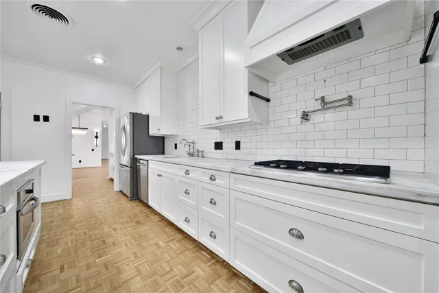 a kitchen with stainless steel appliances a stove a sink and white cabinets