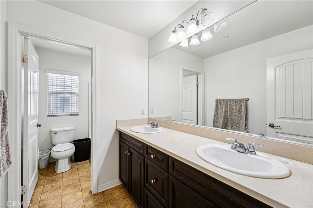 12936 Canopy Court Rancho Cucamonga, CA 91739 - Photo 25 of 32 a bathroom with a double vanity sink mirror and toilet