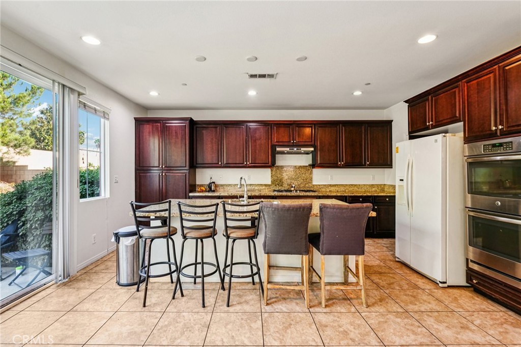 12936 Canopy Court Rancho Cucamonga, CA 91739 - Photo 6 of 32 a kitchen with stainless steel appliances kitchen island granite countertop a refrigerator and a stove top oven