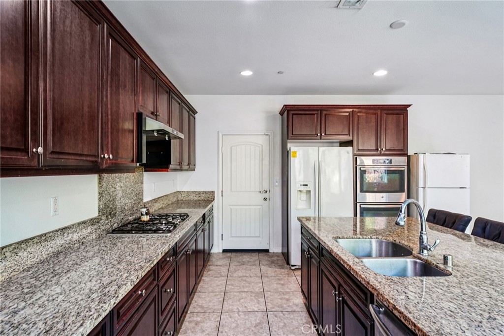 12936 Canopy Court Rancho Cucamonga, CA 91739 - Photo 8 of 32 a kitchen with granite countertop wooden cabinets stainless steel appliances and a sink