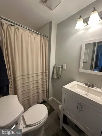 a bathroom with a sink a toilet a mirror and shower curtain