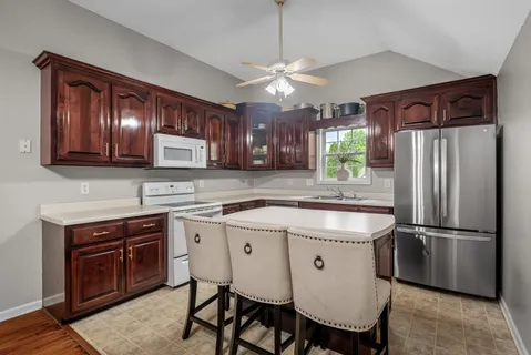 a kitchen with stainless steel appliances granite countertop a table chairs refrigerator and cabinets