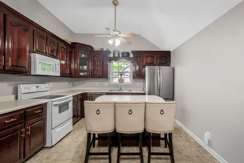 a kitchen with stainless steel appliances granite countertop a sink a stove a refrigerator cabinets and chairs