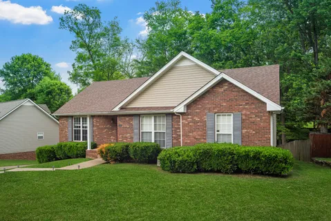a view of a house next to a yard with plants and trees