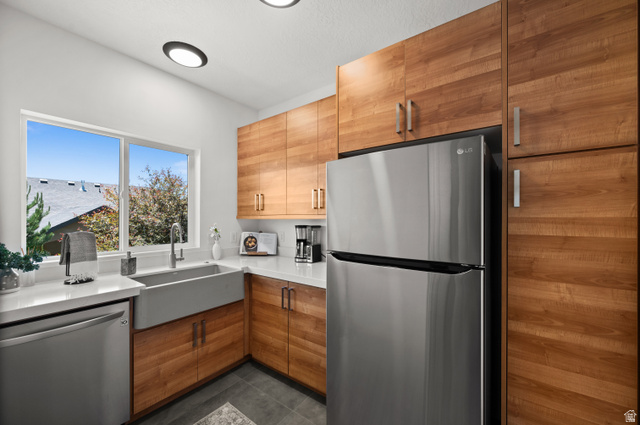 507 West Windmill Gate Cove Draper, UT 84020 - Photo 18 of 46 Kitchen with stainless steel appliances, modern cabinets, dark tile patterned flooring, light stone countertops, and wood finish cabinets