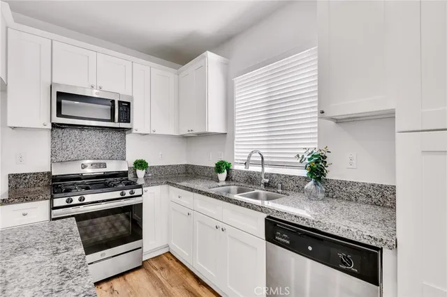 a kitchen with granite countertop a sink and white cabinets