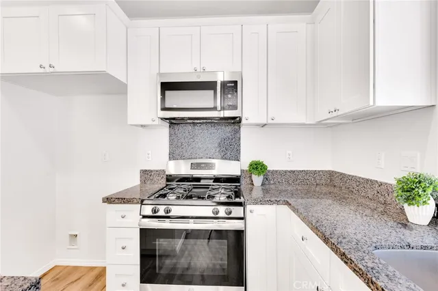 a kitchen with granite countertop white cabinets and stainless steel appliances
