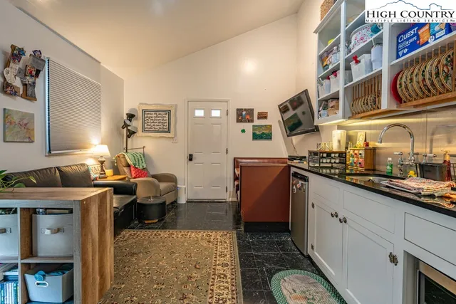 a living room with stainless steel appliances kitchen island granite countertop a sink and cabinets