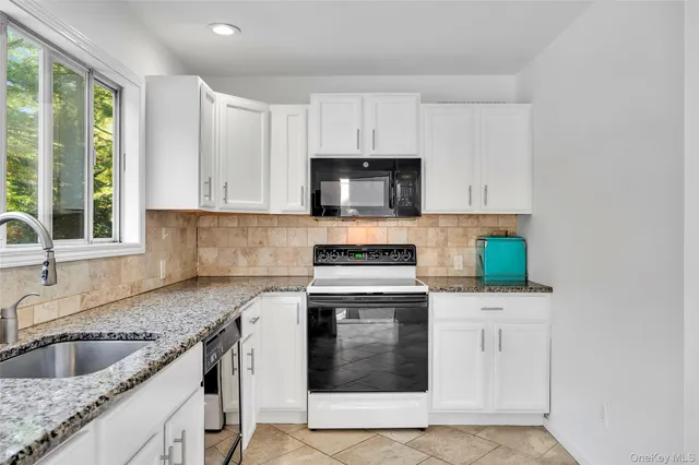 a kitchen with granite countertop a sink a stove and cabinets