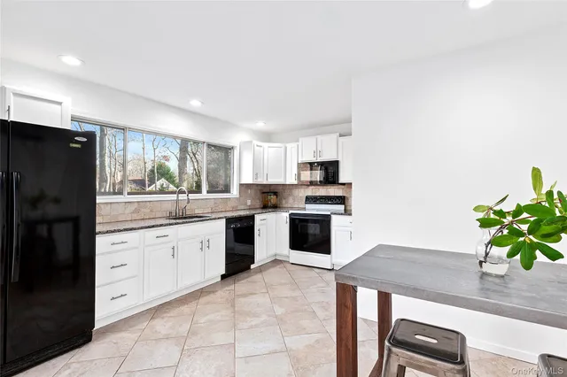 a kitchen with granite countertop a refrigerator a stove a sink a counter space and cabinets