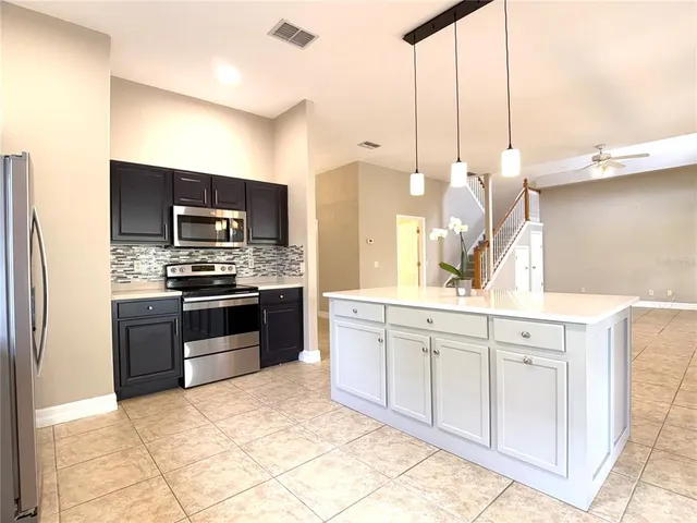 a kitchen with stainless steel appliances kitchen island granite countertop a stove a sink and a microwave