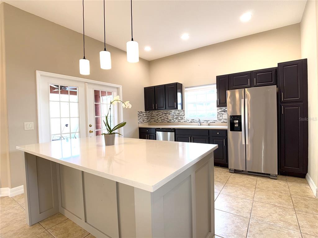 104 Vista Loop Davenport, FL 33897 - Photo 8 of 42 a large kitchen with kitchen island a counter space a refrigerator and a sink