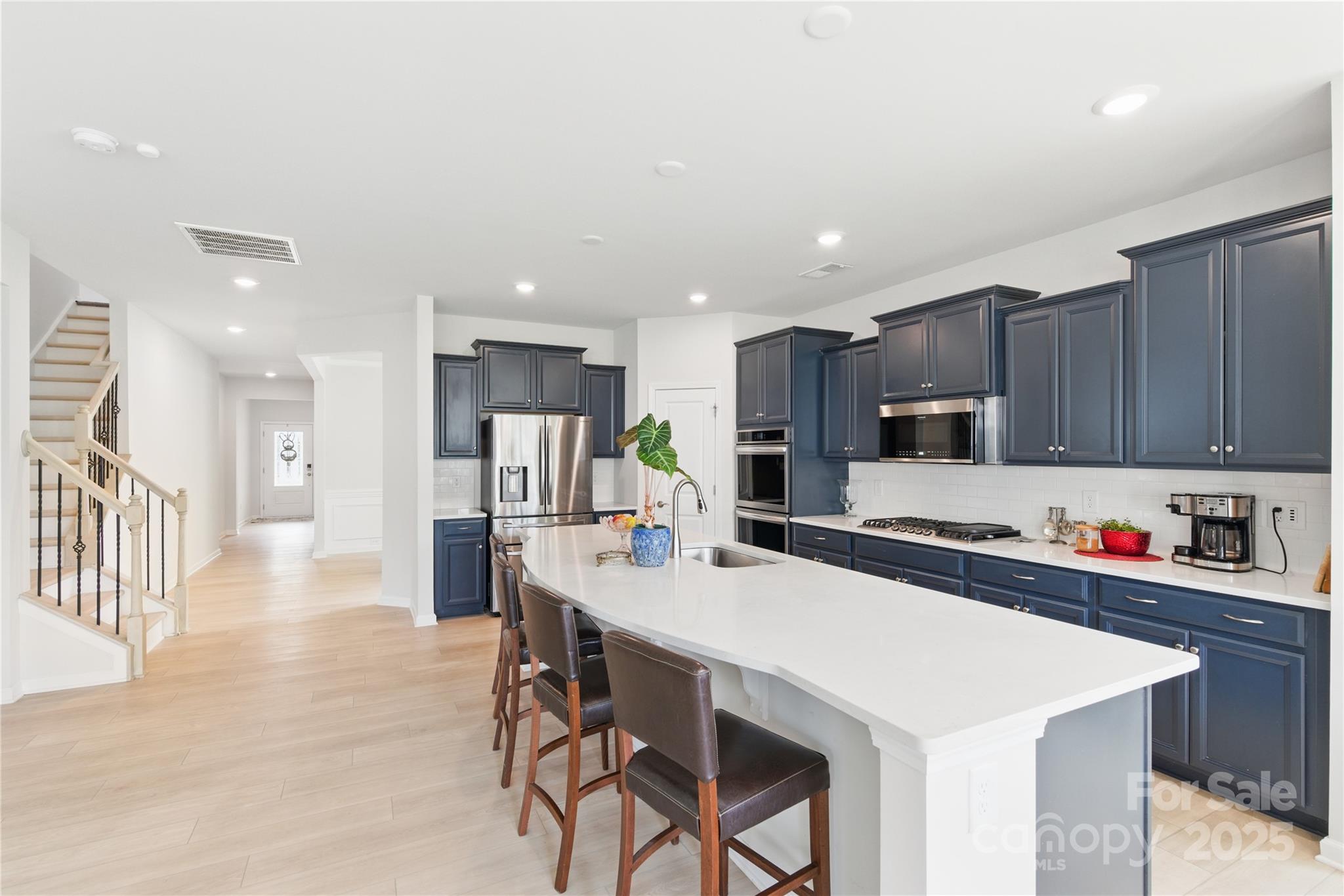 4069 Havenport Circle Tega Cay, SC 29708 - Photo 10 of 48 a kitchen with stainless steel appliances a sink a stove a refrigerator cabinets and a dining table with wooden floor