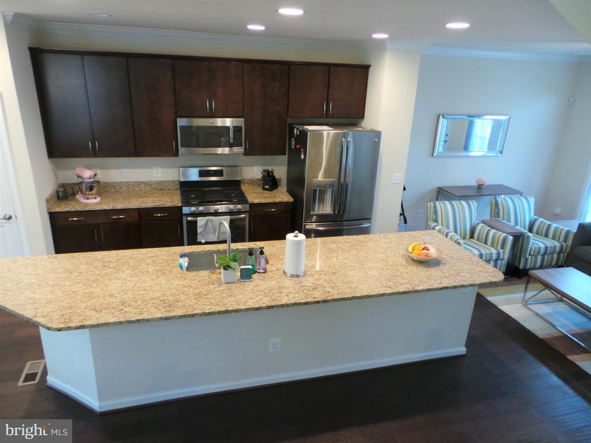 25278 Arrowroot Terrace Chantilly, VA 20152 - Photo 9 of 30 a kitchen with kitchen island granite countertop a sink wooden cabinets and stainless steel appliances