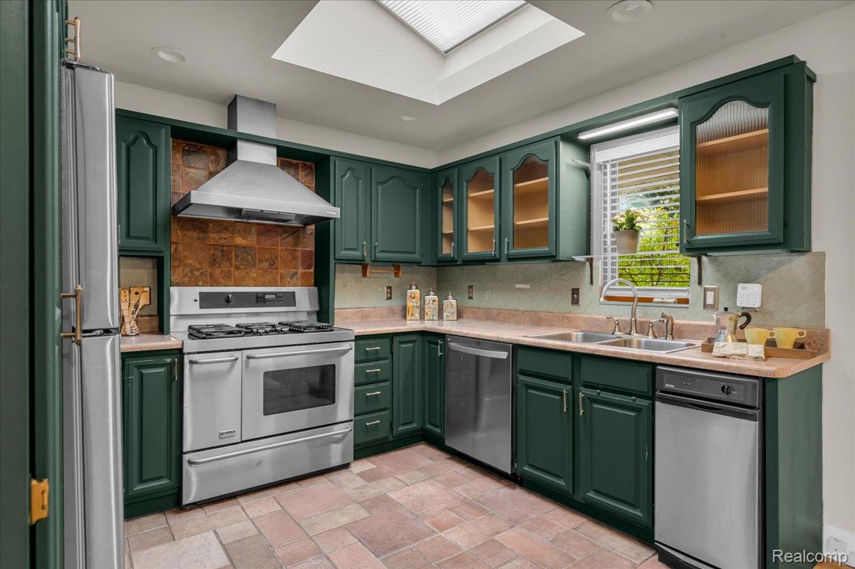 1156 Seneca Road Lake Orion, MI 48362 - Photo 12 of 50 Kitchen featuring green cabinets, glass insert cabinets, appliances with stainless steel finishes, wall chimney exhaust hood, and a skylight